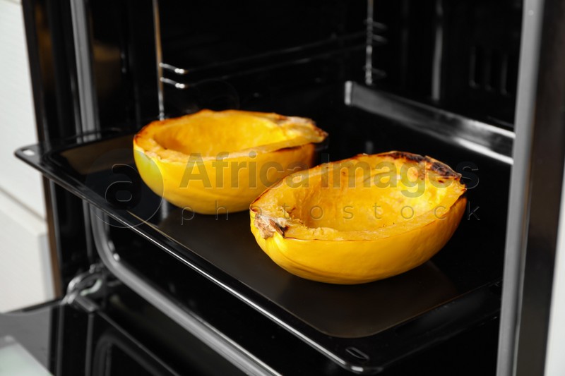 Baking sheet with halves of cooked spaghetti squash in oven