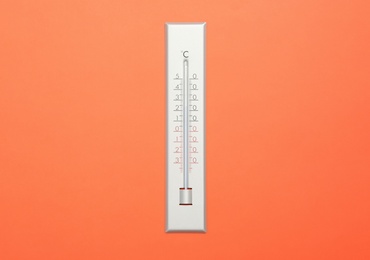 Weather thermometer on orange background, top view