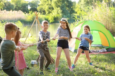 Photo of Little children pulling rope outdoors. Summer camp
