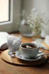 Tray with cup of freshly brewed tea and sugar cubes on wooden table