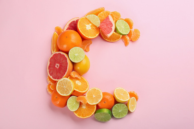 Letter C made with citrus fruits on pink background as vitamin representation, flat lay