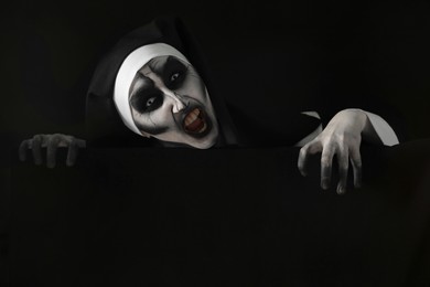 Photo of Portrait of scary devilish nun on black background. Halloween party look