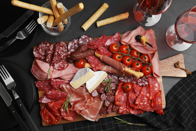 Photo of Tasty ham with other delicacies served on black table, flat lay
