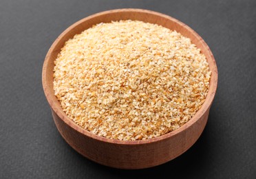 Photo of Wooden bowl of dehydrated garlic granules on grey background