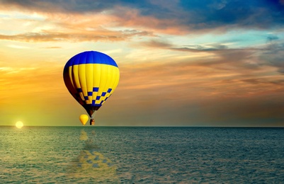 Fantastic dreams. Hot air balloons in sunset sky with clouds over sea