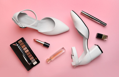Stylish white female shoes and decorative cosmetics on pink background, flat lay