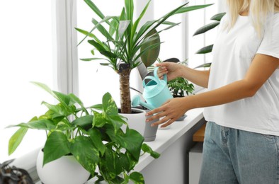 Photo of Woman watering beautiful houseplant on windowsill at home