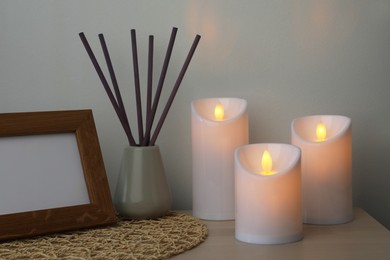 Glowing decorative LED candles on wooden table indoors