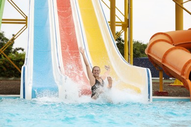 Photo of Young woman sliding into pool in water park