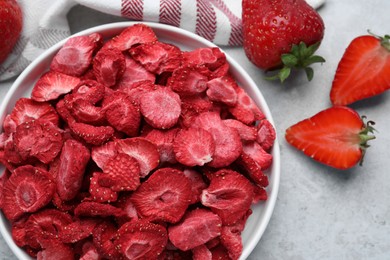 Photo of Freeze dried and fresh strawberries on light grey table, flat lay