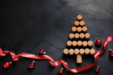Photo of Christmas tree made of wine corks and holiday decoration on dark stone background, flat lay. Space for text