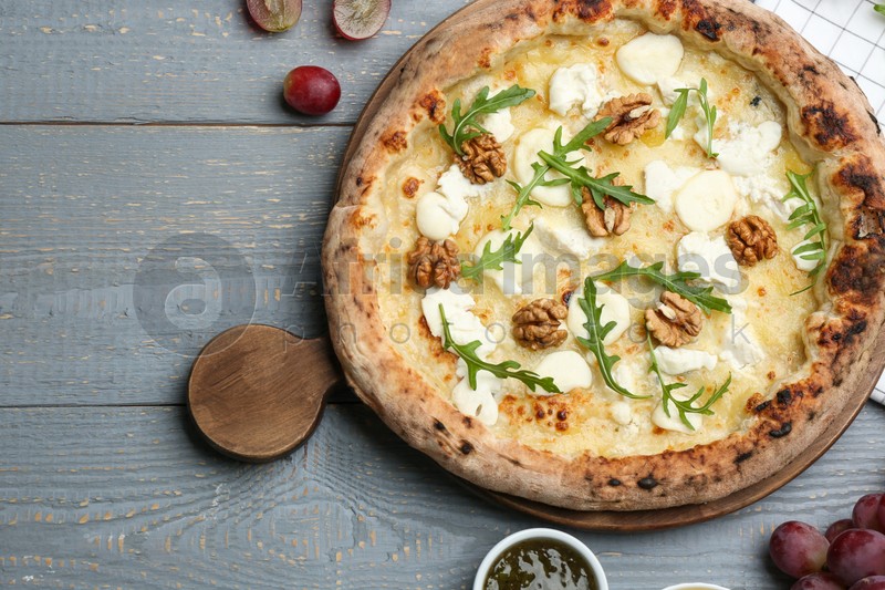 Photo of Delicious cheese pizza with walnuts served on grey wooden table, flat lay