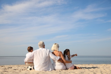 Cute little children with grandparents spending time together on sea beach, back view