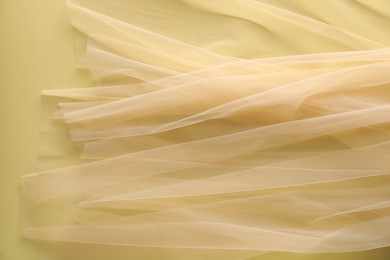 Photo of Beautiful tulle fabric on yellow background, top view