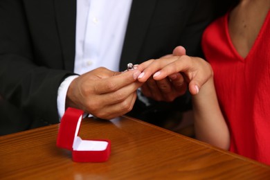 Photo of Man with engagement ring making proposal to his girlfriend at table, closeup