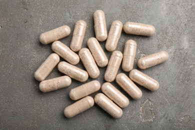 Gelatin capsules on grey table, flat lay