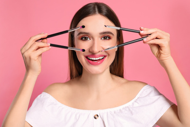 Beauty blogger with makeup brushes on pink background