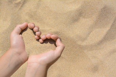 Child holding sand in hands outdoors, closeup with space for text. Fleeting time concept