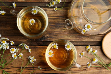 Flat lay composition with tea and chamomile flowers on wooden table