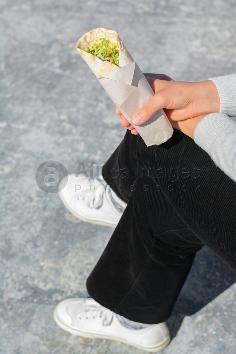 Woman holding delicious vegetable roll outdoors, closeup