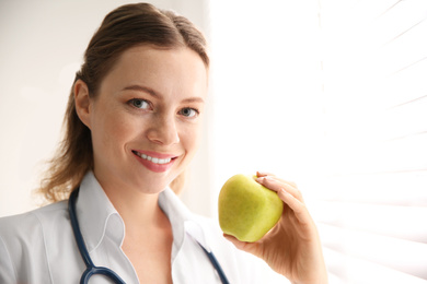 Nutritionist with apple near window in office