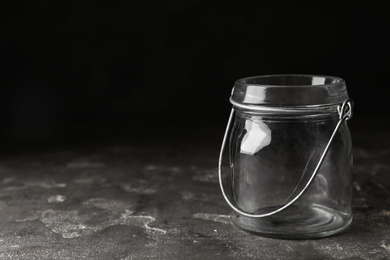 Empty glass jar on grey stone table, space for text