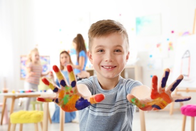 Cute little child showing painted hands at lesson indoors