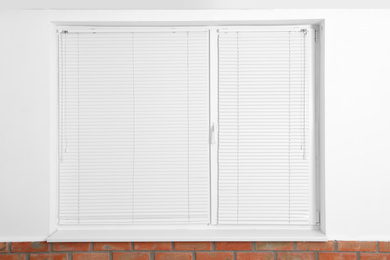 Modern window with closed blinds in room