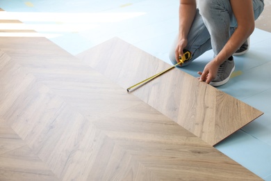 Worker installing laminated wooden floor indoors, closeup