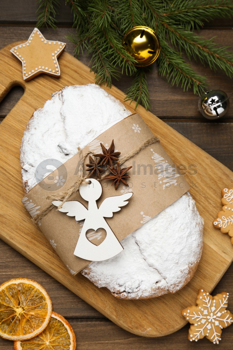 Decorated traditional Christmas Stollen with festive decor on wooden table, flat lay