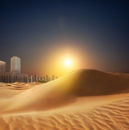 Sandy desert and silhouette of city on horizon at sunset