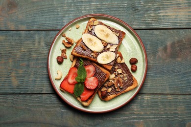 Tasty toasts with chocolate spread, nuts, strawberries, banana and mint served on wooden table, top view