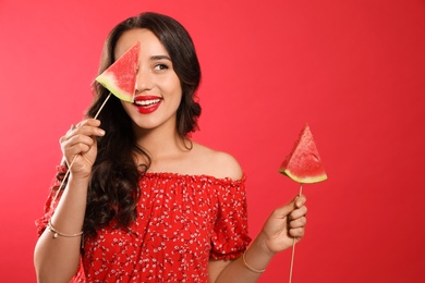 Beautiful young woman with watermelon on red background