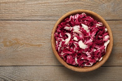 Cut radicchio in bowl on wooden table, top view