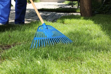 Photo of Gardener raking grass sod on backyard, closeup