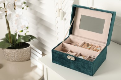 Elegant jewelry box with beautiful bijouterie and expensive wristwatches on white table in room