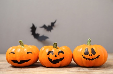 Pumpkins with scary faces near decorative bats on grey background, space for text. Happy Halloween