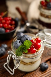 Delicious yogurt parfait with fresh berries and mint on wooden table, closeup