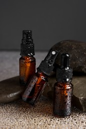 Bottles of organic cosmetic products and stones on wet surface