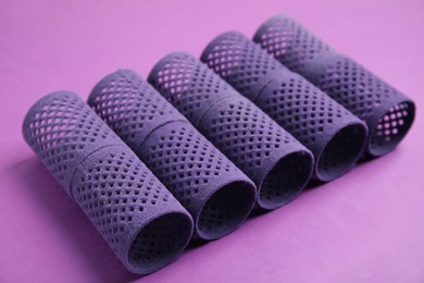 Photo of Hair curlers on lilac background, closeup. Styling tool