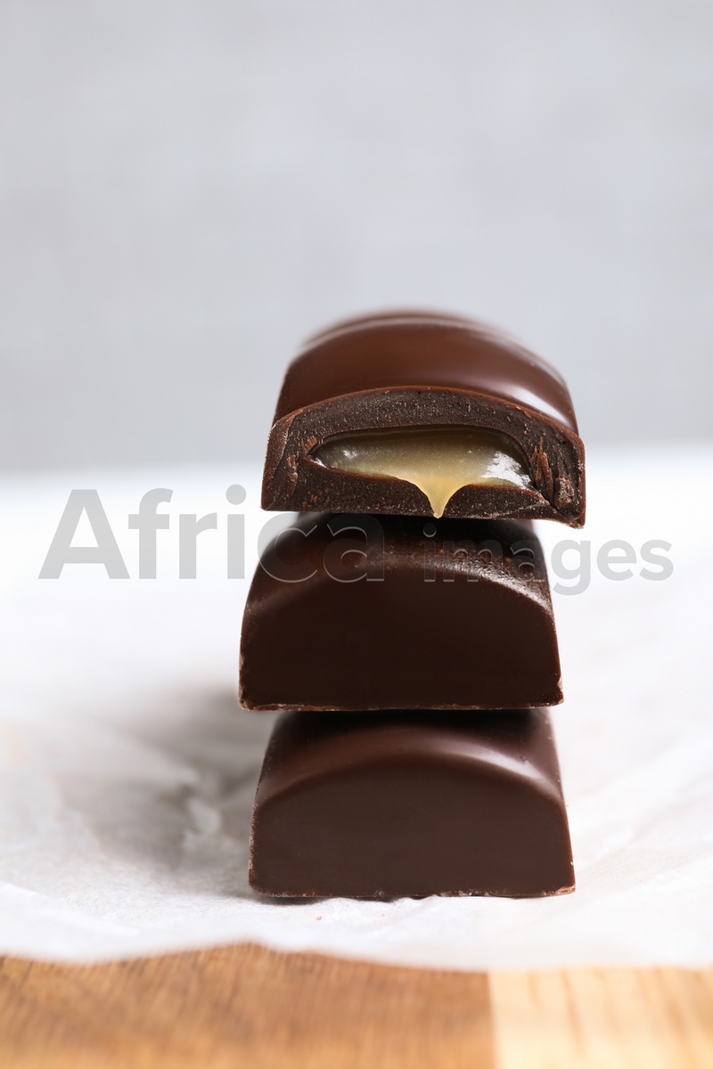 Pieces of chocolate with caramel filling on wooden table, closeup