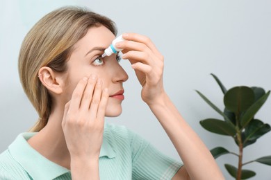 Young woman using eye drops at home