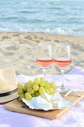 Glasses with rose wine and snacks for beach picnic on sandy seashore