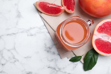 Tasty freshly made grapefruit juice and fruits on white marble table, flat lay. Space for text