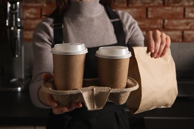 Photo of Barista with takeaway coffee and dessert in cafe, closeup