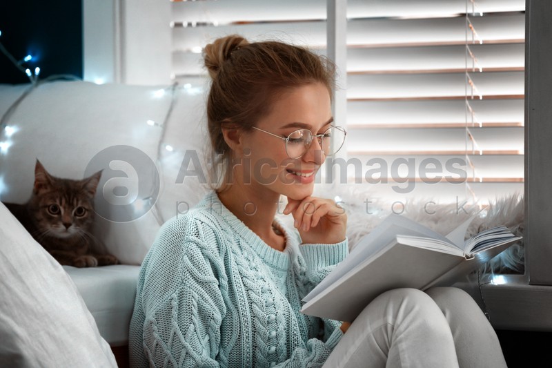 Young woman reading book at home. Cozy winter