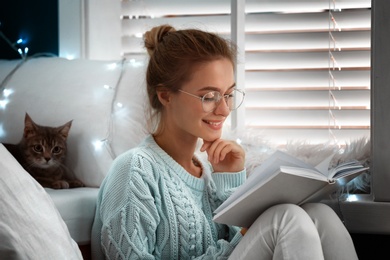 Young woman reading book at home. Cozy winter