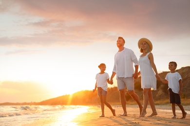 Happy family on sandy beach near sea at sunset