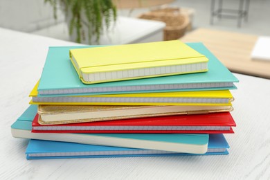 Stack of colorful planners on white wooden table indoors