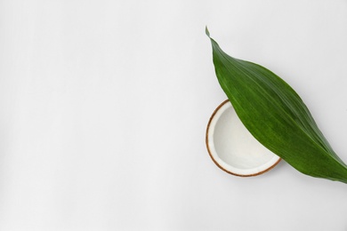 Half of fresh coconut and palm leaf on white background, top view